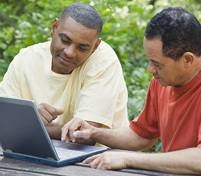 Two men use a laptop computer