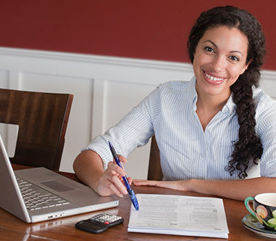 A busy woman working at a laptop.