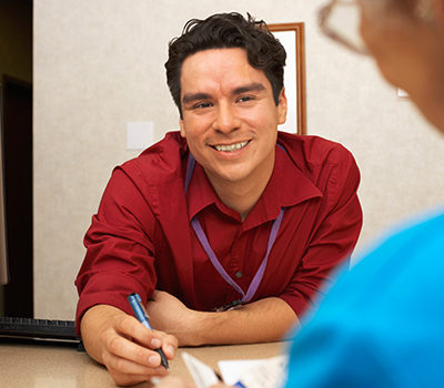 A man smiling at a woman sitting from across a desk