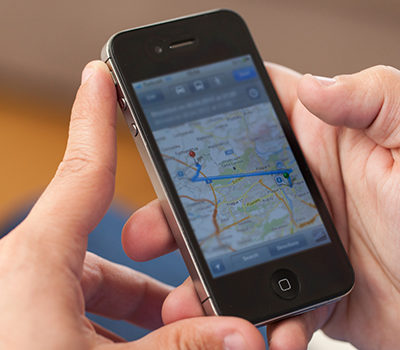 A pair of hands holding an iPhone that displays a map.