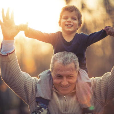 A grandfather giving his grandson a ride on his shoulders