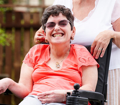 A disabled woman in a wheelchair with her care mother in garden