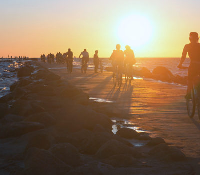 People watching the sunset on a boardwalk.