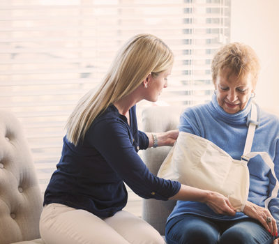 younger woman helping elderly woman in a sling