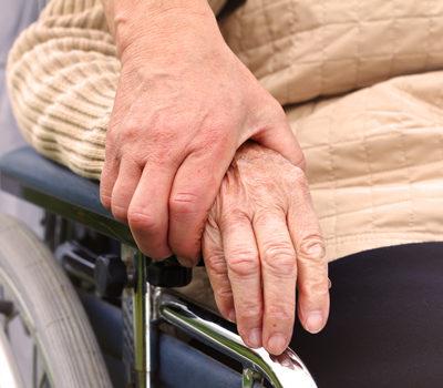 A hand of a younger person holding the hand of an elderly person.