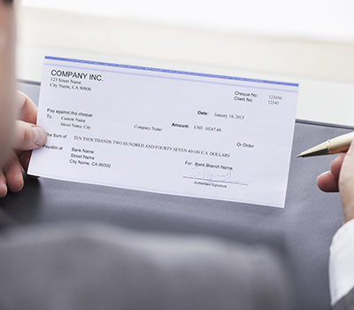 A close-up of a businessman filling blank cheque