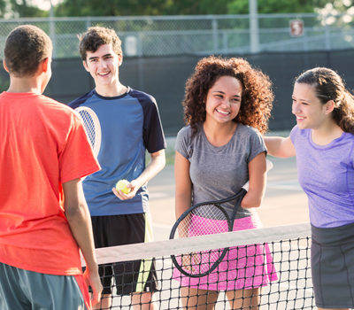 Two boys and two girls playing tennis together