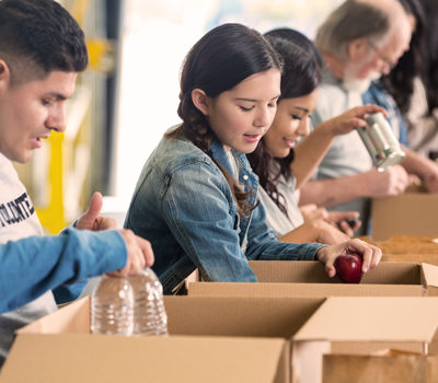 People filling canned goods into boxes