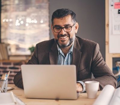 A man smiling while using a laptop