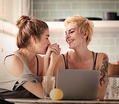 Two women holding hands while smiling at each other