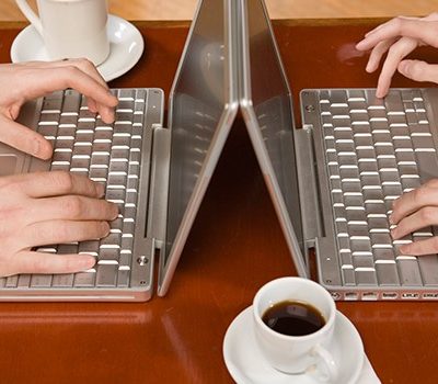 Two people sitting across from one another each with a laptop