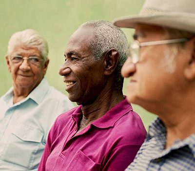 Three elderly men sitting together while smiling