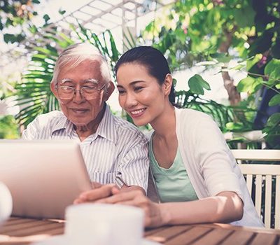 A woman and elderly man on laptop