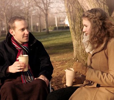 A man and woman drinking coffee and sitting together outside