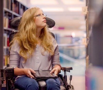 A woman in a wheelchair inside of a library