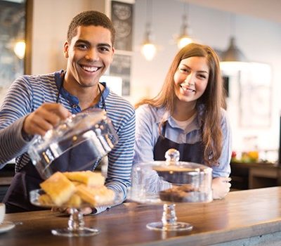 A man and woman working the counter of a bakery