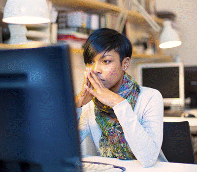 A woman reading from a computer monitor while sitting at a desk