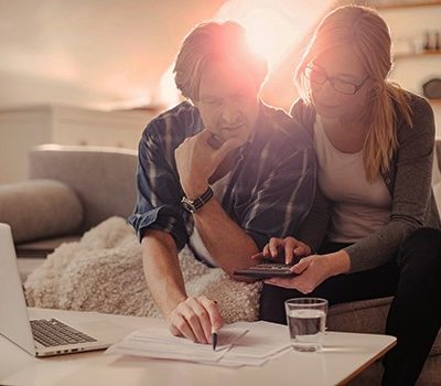 A couple sitting on a couch reviewing documents on a coffee table