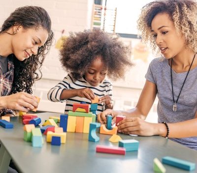 Two women and a baby playing with blocks