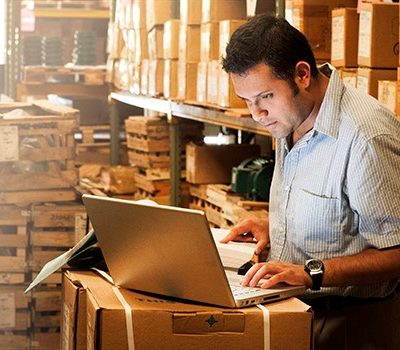 A man using a laptop that is on a stack of boxes