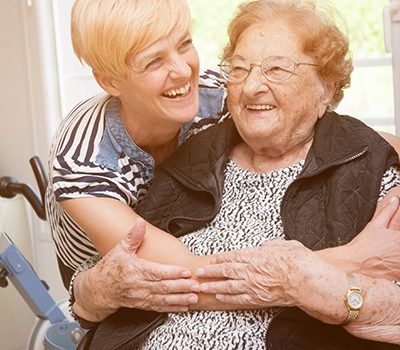 An elderly woman and her daughter embracing one another