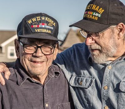 Two older men wearing veteran hats