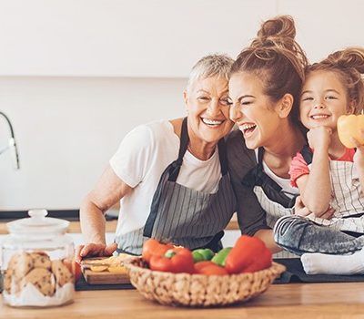 A grandmother smiling and laughing with her daughter and grandaughter