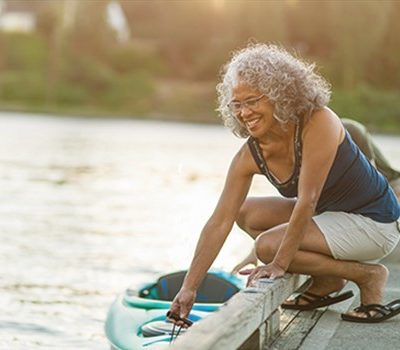 A woman setting a kayak into the water by a dock