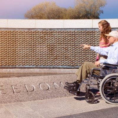 A man in wheel chair and woman looking at a war memorial