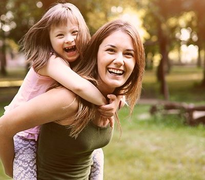 A little girl getting a piggy back ride on older woman