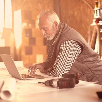 An older man using a laptop inside a workshop