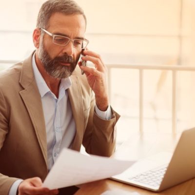 A man reviewing a document while using a cellphone