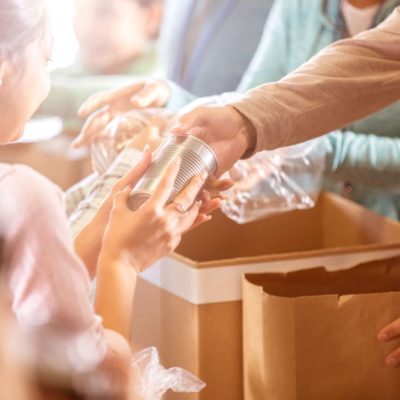 A photo of a woman handing a can from a bag to a teenage girl