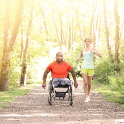 A man in a wheelchair accompanying a woman jogging