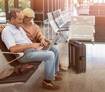 A older couple using a laptop while sitting at an airport