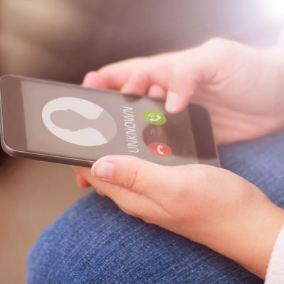 A woman holding a cellphone that is ringing from an unknown caller