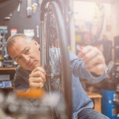 A man in a workshop fixing a bicycle wheel