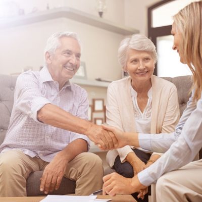 An elderly couple having a discussion with a younger woman.