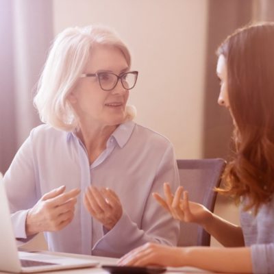 An older woman and her daughter having a conversation in front of a laptop.