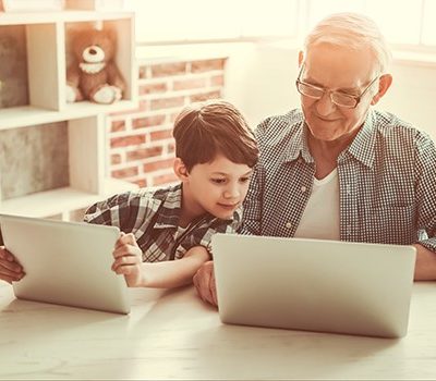 A grandfather and grandson looking at a laptop.