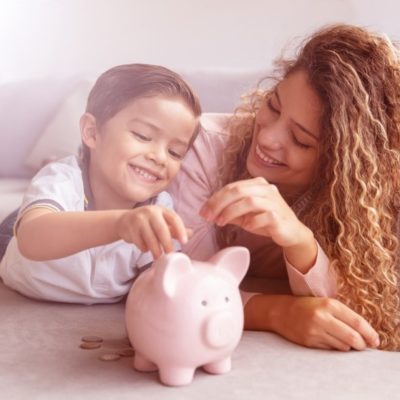 A mother and daughter putting loose change into a piggy bank.