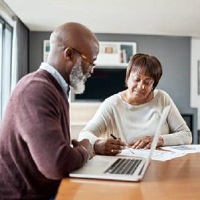 An older couple reviewing paperwork and using laptop