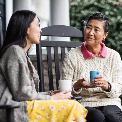 Adult woman and senior mother talking on front porch