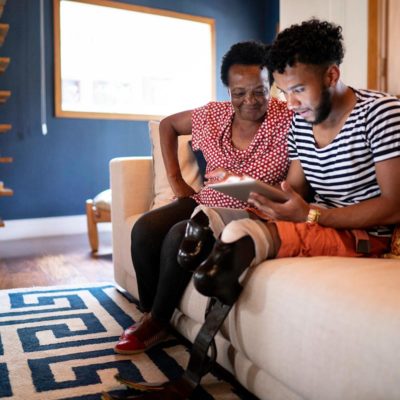 A mother and son sitting on a couch while looking at a tablet device