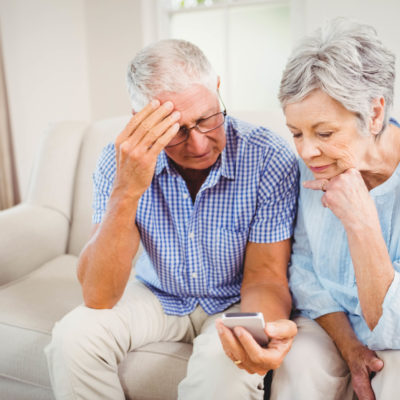 Sad senior couple looking at mobile phone