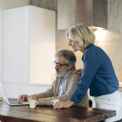 Mature man with wife using laptop on kitchen table at home