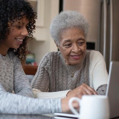 A younger woman teaching older woman on laptop (for post)