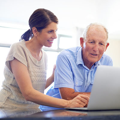 A senior man looking at something on his daughter's laptop