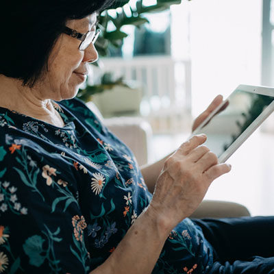 Senior woman using digital tablet while relaxing on the sofa in the living room at home