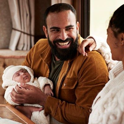 father holding a newborn baby smiling with the mother